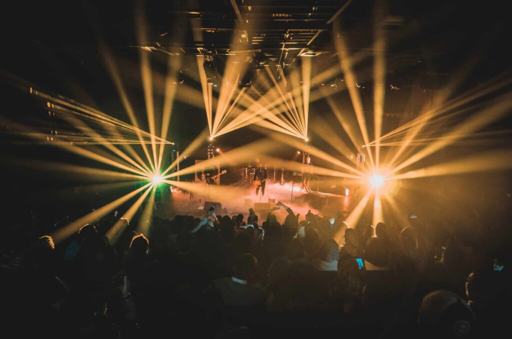 En koncertsal med et band der spiller for et publikum i skæret af orange lys.