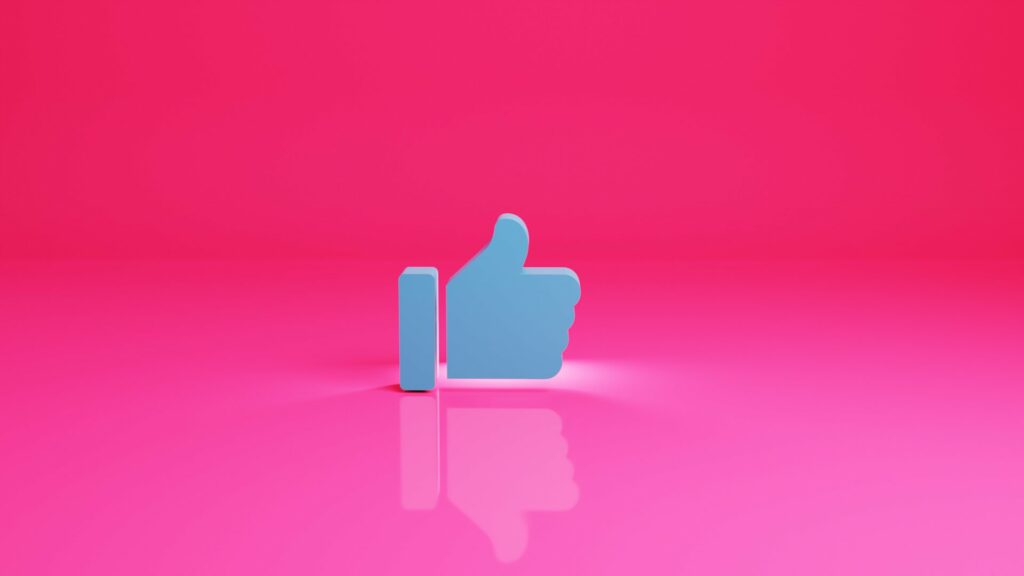 Et billede af en thumbs up / tommelfinger op ikon med en lyserød baggrund.